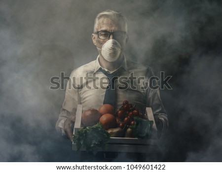 Businessman with protective mask holding a crate with polluted poisonus vegetables, food pollution concept