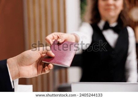 Businessman providing passport for check in process, giving identification documents to receptionist at front desk. Adult arriving at hotel for registration, id papers in lobby. Close up.