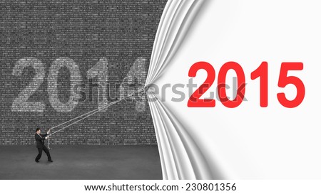businessman pulling down 2015 curtain covering old 2014 brick wall on gray concrete floor
