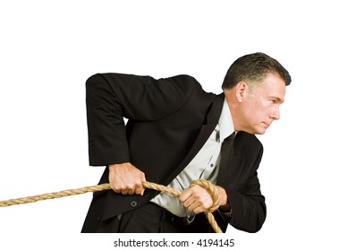 A businessman pulling on a rope as if dragging or struggling against something.