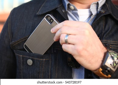 businessman pulling out a mobile phone or may be putting mobile in pocket