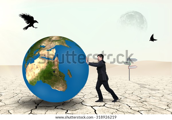 Businessman pushes world sphere in desert .Elements\
of this image furnished by\
NASA