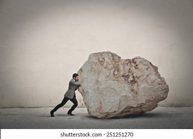 Businessman pushing a boulder  - Shutterstock ID 251251270