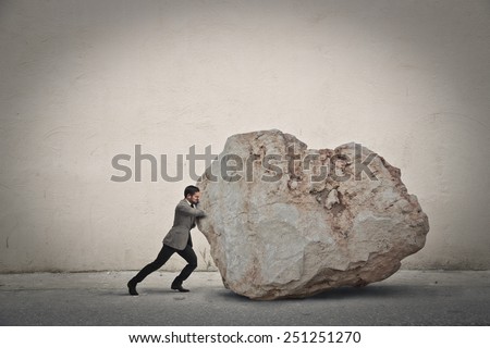 Businessman pushing a boulder 
