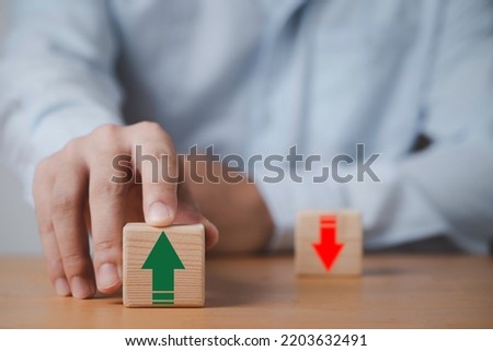 Businessman pushing green up arrow which print screen on wooden cube block for financial planing of interest rate , mortgage ranking , price and inflation growth concept.