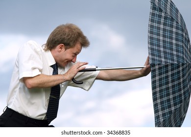 Businessman Pushing Umbrella Against Strong Wind