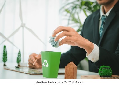 Businessman put paper waste on small tiny recycle bin in his office symbolize corporate effort on eco-friendly waste management by recycling for greener environment and zero pollution. Gyre - Powered by Shutterstock