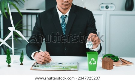 Businessman put paper waste on small tiny recycle bin in his office symbolize corporate effort on eco-friendly waste management by recycling for greener environment and zero pollution. Gyre