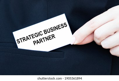 A Businessman Puts A Business Card With A STRATEGIC BUSINESS PARTNER In His Pocket.