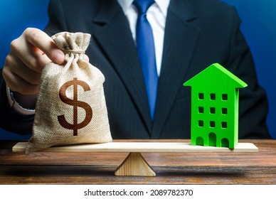 Businessman puts dollar money bag on scales and green house. Profitability housing of eco technologies. Investment in renovation. Reduced CO2 emissions, energy efficiency. Payback period