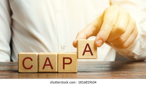 Businessman puts wooden blocks with the word CAPA. Corrective and Preventive action plans. Business management concept. Strategy and efficiency. Improving organizational processes. Performance