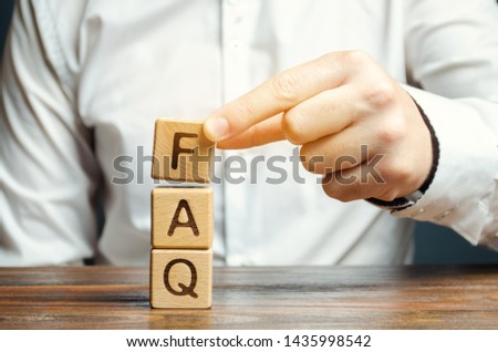 Businessman puts wooden blocks with the word FAQ (frequently asked questions). Collection of frequently asked questions on any topic and answers to them. Instructions and rules on Internet sites