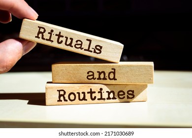 Businessman puts wooden blocks with the words rituals and routines.