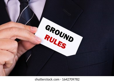 Businessman Putting A Card With Text Ground Rules In The Pocket