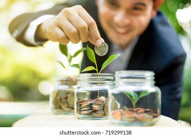 Businessman putting coin into the glass jar with young plant, demonstrating financial growth through saving plans and investment schemes - Powered by Shutterstock