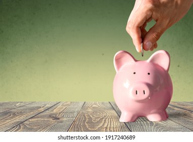 Businessman Putting Coin Into The Piggy Bank