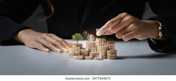 Businessman putting coin on stack with growing small tree symbolizing investment growth and saving money - Powered by Shutterstock