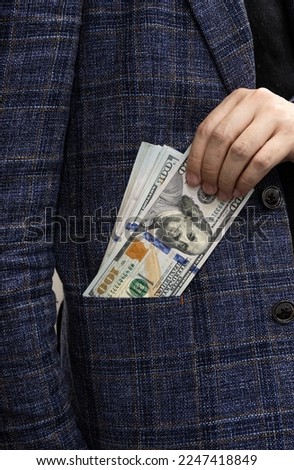 Businessman putting dollars bills in the pocket