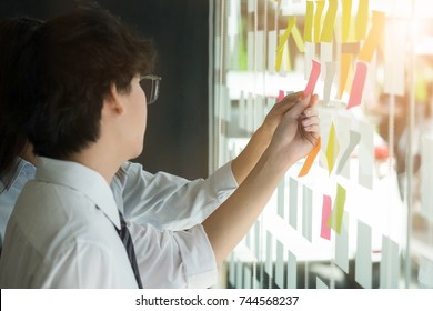  businessman putting his ideas on paper note a presentation in conference room. Focus in hands with marker pen writing.