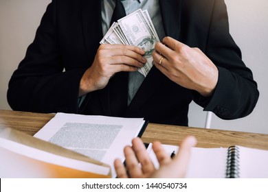 Businessman Putting Stack Of Money Bills In His Suit Coat Pocket.