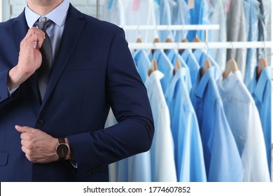 Businessman and rack with clean clothes at dry-cleaner's, closeup. Space for text 
