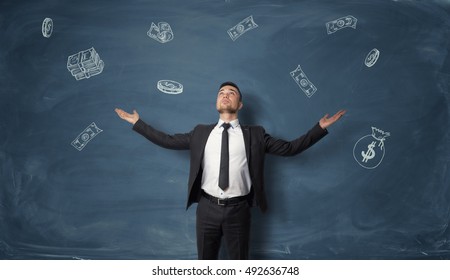 Businessman raised his hands palm up   looks at falling dollar bills  bags money   coins  The look into the future  Prosperous business   economy  To be in easy circumstances 