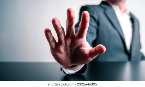 Businessman raising hand in front of prohibiting or stopping forbid and invalid gesture sign on black table and white background. Corruption warning and illegal concept. Anti-corruption and restrain.