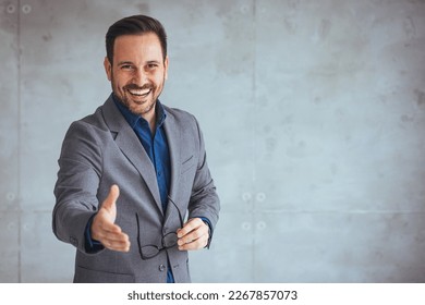 Businessman reaching out his hand for a handshake. Confident businessman stretching his hand for greeting. Friendly young man in formal attire hr recruiter stretching hand to camera  - Powered by Shutterstock