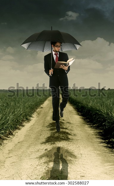 Businessman Reading Book Under Umbrella Shot 스톡 사진(지금 편집) 302588027