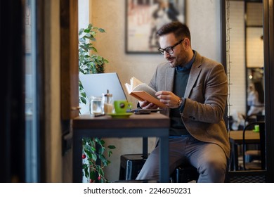 Businessman Reading Book while Sitting in Cafe
