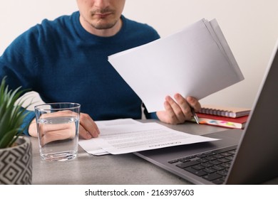 Businessman Reading Contract Before Signing It. Man Reading Contract Terms. Closeup Businessman Reading Business Contract Documents At Desk With Laptop Computer, Busy With Paperwork.