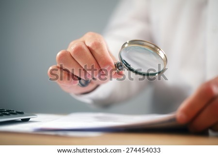 Businessman reading documents with magnifying glass concept for analyzing a finance agreement or legal contract