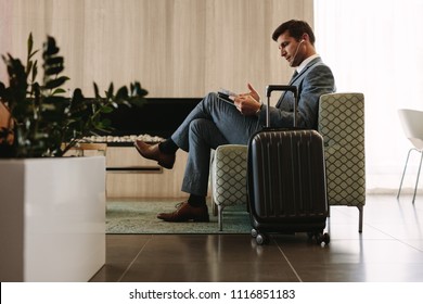 Businessman reading a magazine while waiting for his flight at airline terminal lounge. Entrepreneur at airport waiting area reading a magazine. - Powered by Shutterstock