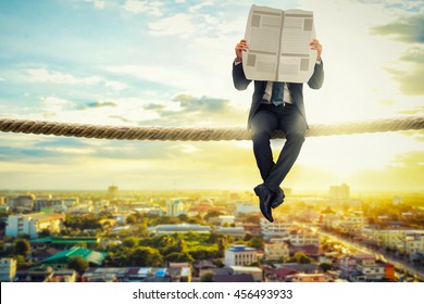 Businessman Reading News Paper On Rope In The Morning