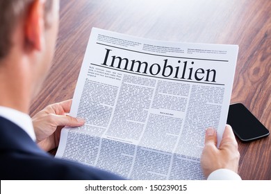 Businessman Reading Newspaper With The Headline Real Estate