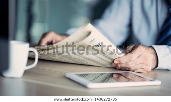 Businessman reading the\
newspaper on table