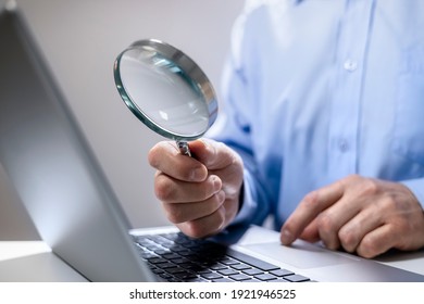 Businessman reading online documents on laptop screen with magnifying glass concept for analyzing a finance agreement or legal contract