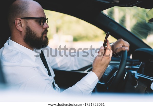 Businessman reading received smartphone\
notification while using self-driving in contemporary car with\
autopilot, male tracking gps location via cellphone application\
connected to 4g\
wireless