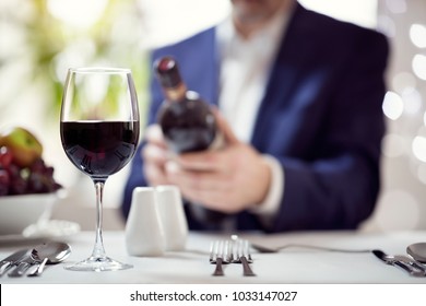 Businessman Reading Red Wine Bottle Label In Restaurant Concept For Business Lunch Or Dinner Meeting