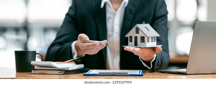 Businessman or real estate agents holding house model offering to his client after signing the sale at the office. - Powered by Shutterstock