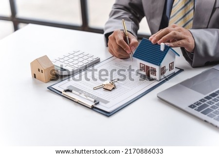 Businessman realtor with house model, sitting at desk, real estate agent manager working on documents, mortgage and property.