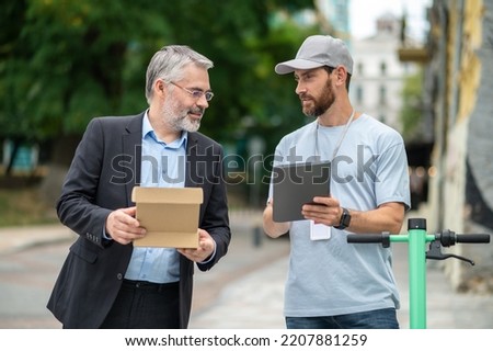Businessman receiving a delivery box from the courrier on a scooter