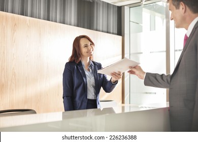 Businessman Receiving Document From Receptionist In Office