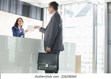 Businessman Receiving Document From Receptionist In Office