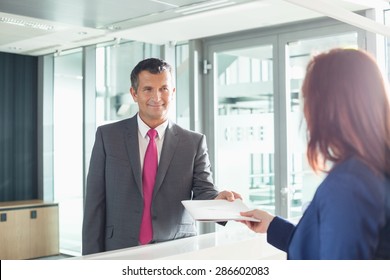 Businessman receiving document from receptionist in office - Shutterstock ID 286602083