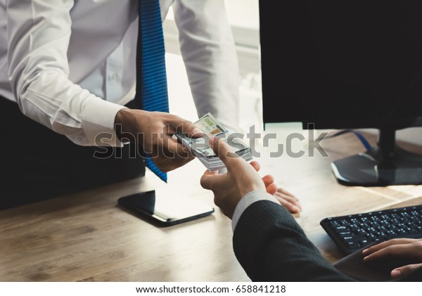 Businessman\
receiving money from his partner at working desk in the office -\
loan, bribery and corruption\
concepts