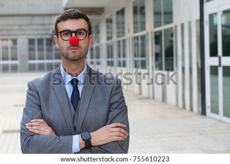 Businessman with a red clown nose crossing his arms