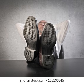 Businessman Relaxing At The Office With His Feet On The Table