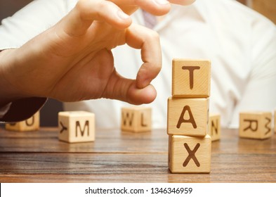 Businessman removes wooden blocks with the word Tax. The concept of reducing the tax burden. Tax avoidance. Costs and expenses of the business. Taxation. Pay off debt. Freedom from illegal taxes