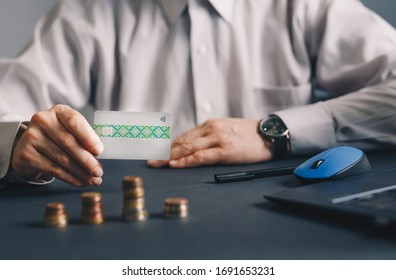 Businessman representing a credit card and has on the table a staircase of the economy with coins - Shutterstock ID 1691653231
